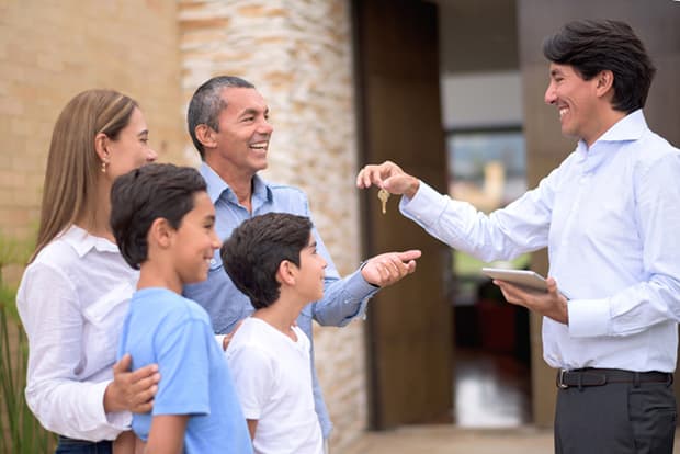 Real estate agent giving keys of their new house to a happy Latin American family.