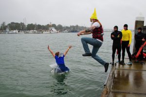 Two people dressed in elf costumes jumping into the lake 