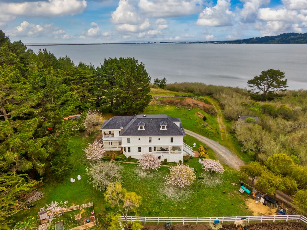 Aerial Shot of white home on a hill overlooking the bay