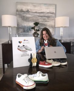 woman sitting at table with shoes and computer in front of her.